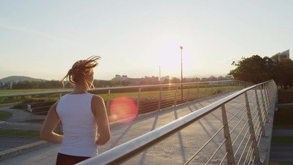 SLOW MOTION: Sporty woman jogging over the bridge in city on sunny morning - Powered by Adobe