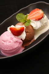 Tasty chocolate, vanilla and strawberry ice cream scoops in bowl