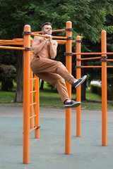 Fototapeta premium young man doing pull ups on horizontal bar outdoors.