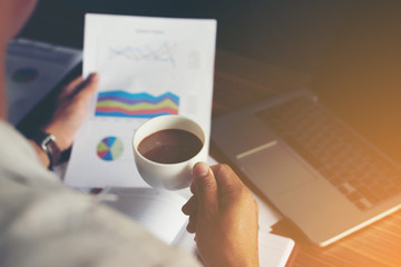 Businessman analysis financial graph and holding a cup of coffee