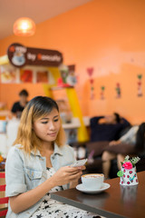 Close-up of woman text messaging with her mobile at coffee shop.