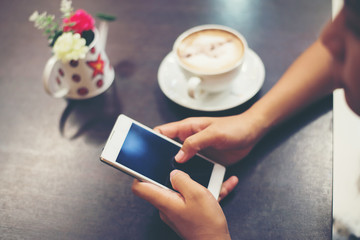 Close-up of woman hands text messaging with her mobile at coffee