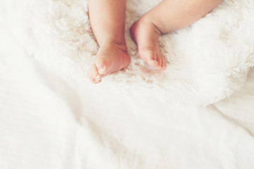 Newborn Baby legs on white bed.