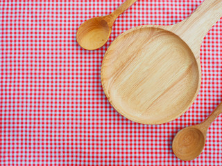 Empty plate and spoons on red checked tablecloth