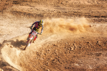Motocross rider creates a large cloud of dust and debris