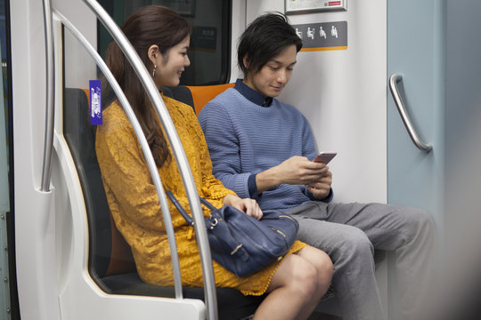 Young couple looking at a smart phone on a train