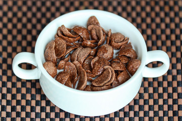 Chocolate cereal with milk in white bowl