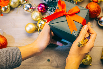 man hand holding gift box with a pen in his right hand.