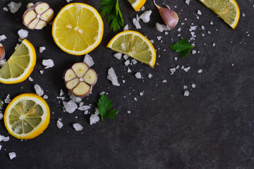 Black food background with slices of lemon, salt and garlic 