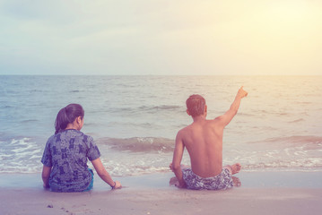 The boy pointing to the sea and girl look on the sea