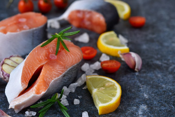 Fresh raw salmon steak with lemon and salt on black marble 