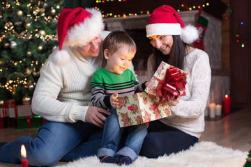 Fototapeta na wymiar holidays, presents, christmas concept - happy mother, father and kid boy opening gift box