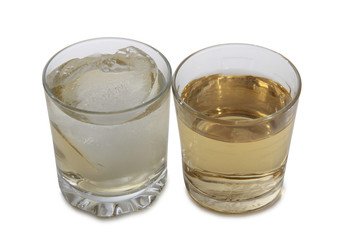 Glass jars with whiskey and ice on white background