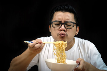 Asian man eating Instant noodles on black background