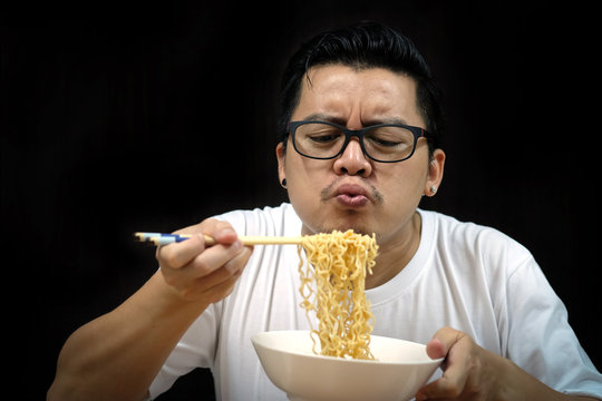 Asian Man Eating Instant Noodles On Black Background