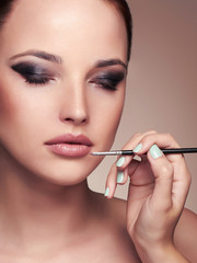 Beautiful woman face. beauty girl with Perfect make-up.Makeup artist applies lipstick.cosmetics