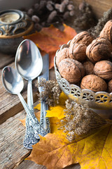 Silver plate with walnuts, candle, autumn leaves and spoons 