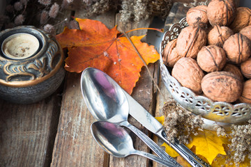 Silver plate with walnuts, candle, autumn leaves and spoons 