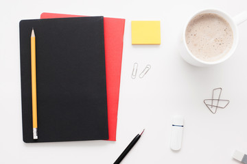 Office worker stuff on white background, flat lay. Top view on businessman workplace - notebook, pen, clips, stickers, memory card and cup of coffee, free space