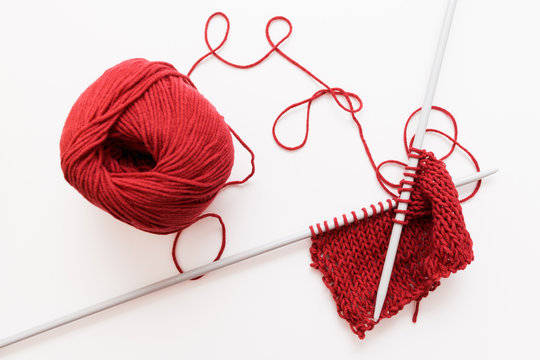 Red Woolen Thread And Knitting Needle Isolated On White Background. Sample Of Bordo Knitted Cloth With Worktools. Handiwork, Leisure, Hobby Concept