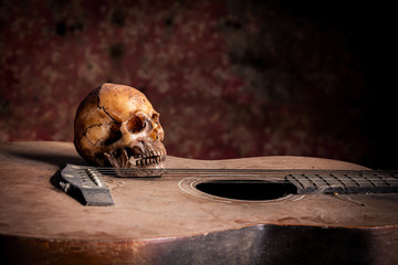 Still life with human skull on guitar background