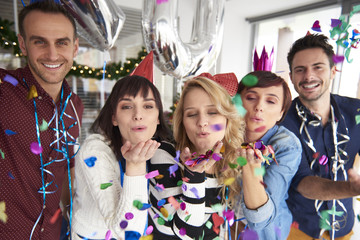 Friends blowing pieces of confetti.