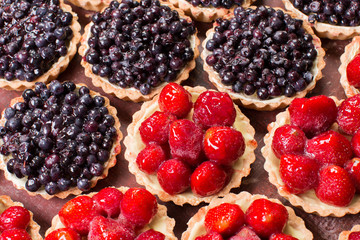 Fresh summer berries in a tartlets on a wooden background.