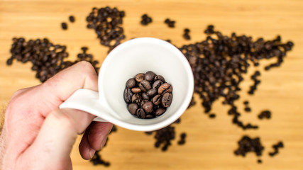 man is holding white ceramic cup full of coffee beans