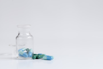 colored pills in glass jar on white background