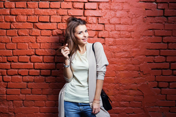 Young beautiful happy woman in casual cloths against brick wall