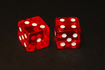two dice on a black desk, result seven (7), three (3) and four (