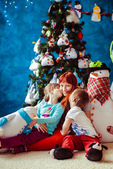 Fototapeta na wymiar Children kiss her mom next to the Christmas tree