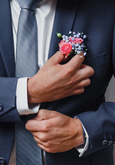 groom boutonniere adjusts his hand in a jacket pocket
