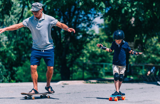 Skateboard lesson. Grandfather and grandson skateboarding together