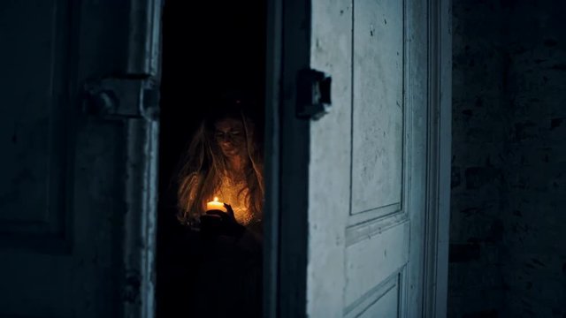 Dead bride with a candle in hand in an abandoned house at night.