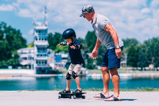 Skateboarders. Grandfather and grandson trying a snakeboard