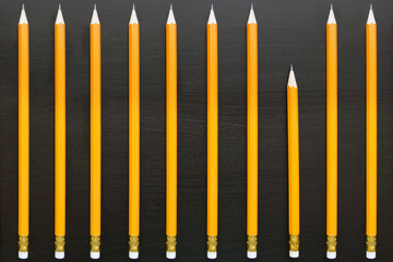 Row of identical long pencils with one different short