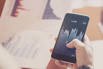 Girl with a smart phone analyzing market exchange rates.