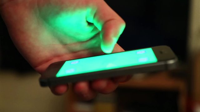 Main et smartphone sur fond vert pour incrustation - lueur verte