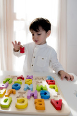 Kid practice reading looking at wooden letters on the table