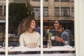 View Through Window Of Couple Enjoying Drink In Coffee Shop