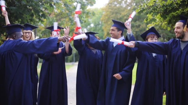 happy students in mortar boards with diplomas