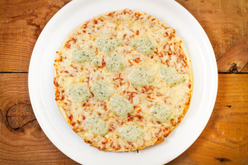 Pizza con mozzarella y tomate sobre una tabla de madera rústica. Vista superior