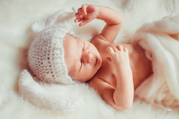 newborn lying on blanket in a white hat rabbit