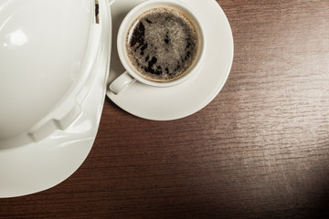 Top view of a paper cup of black coffee on wooden table