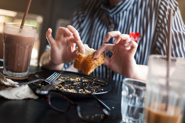 Woman eating croissant in cafe
