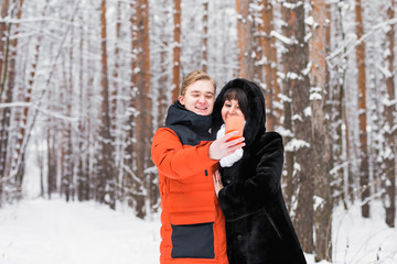 happy couple taking selfie by smartphone in winter