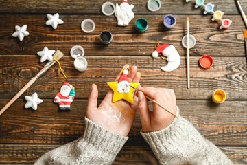 Girl in a bright sweater paints porcelain figurines.