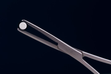 round pill held by medical forceps