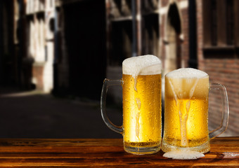 cold mug of beer with foam on the background of the street